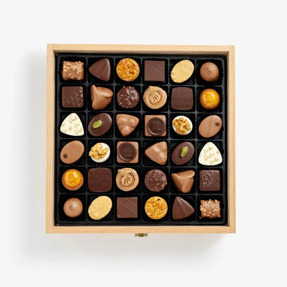 Assorted chocolates in a wooden box on a white background