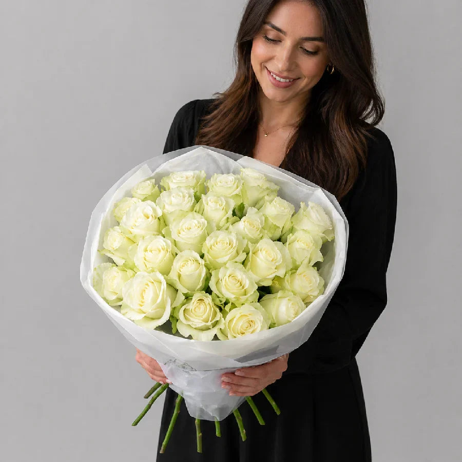 Woman holding a bouquet of white roses against a gray background