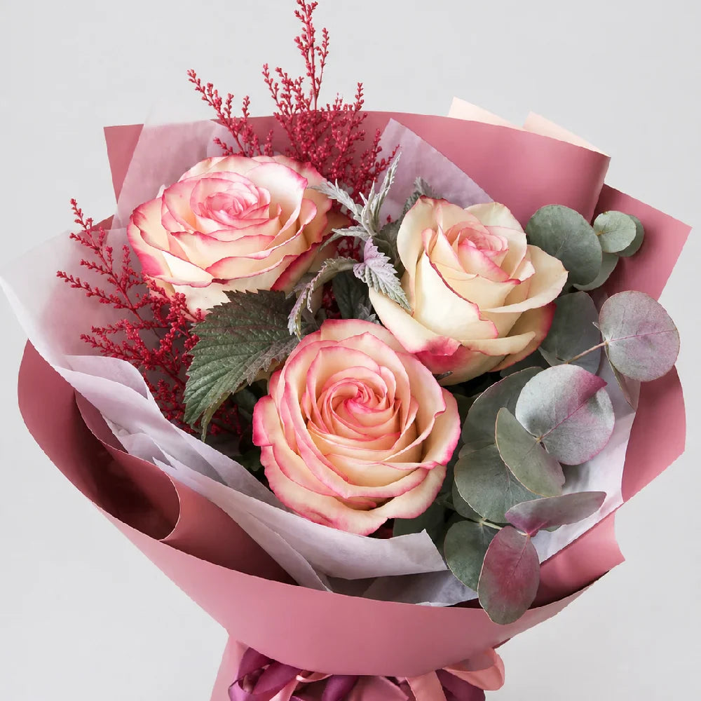 Bouquet of pink roses with green leaves and red accents on a light gray background