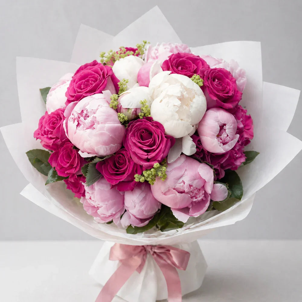 Bouquet of pink and white flowers with a pink ribbon on a light gray background