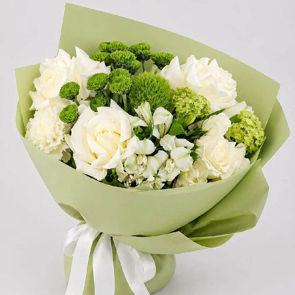 Bouquet of white and green flowers wrapped in green paper with a white ribbon on a light gray background