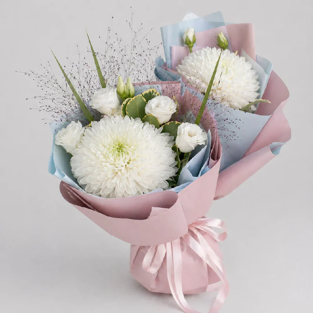 Bouquet of white flowers wrapped in pink paper with a bow on a light gray background