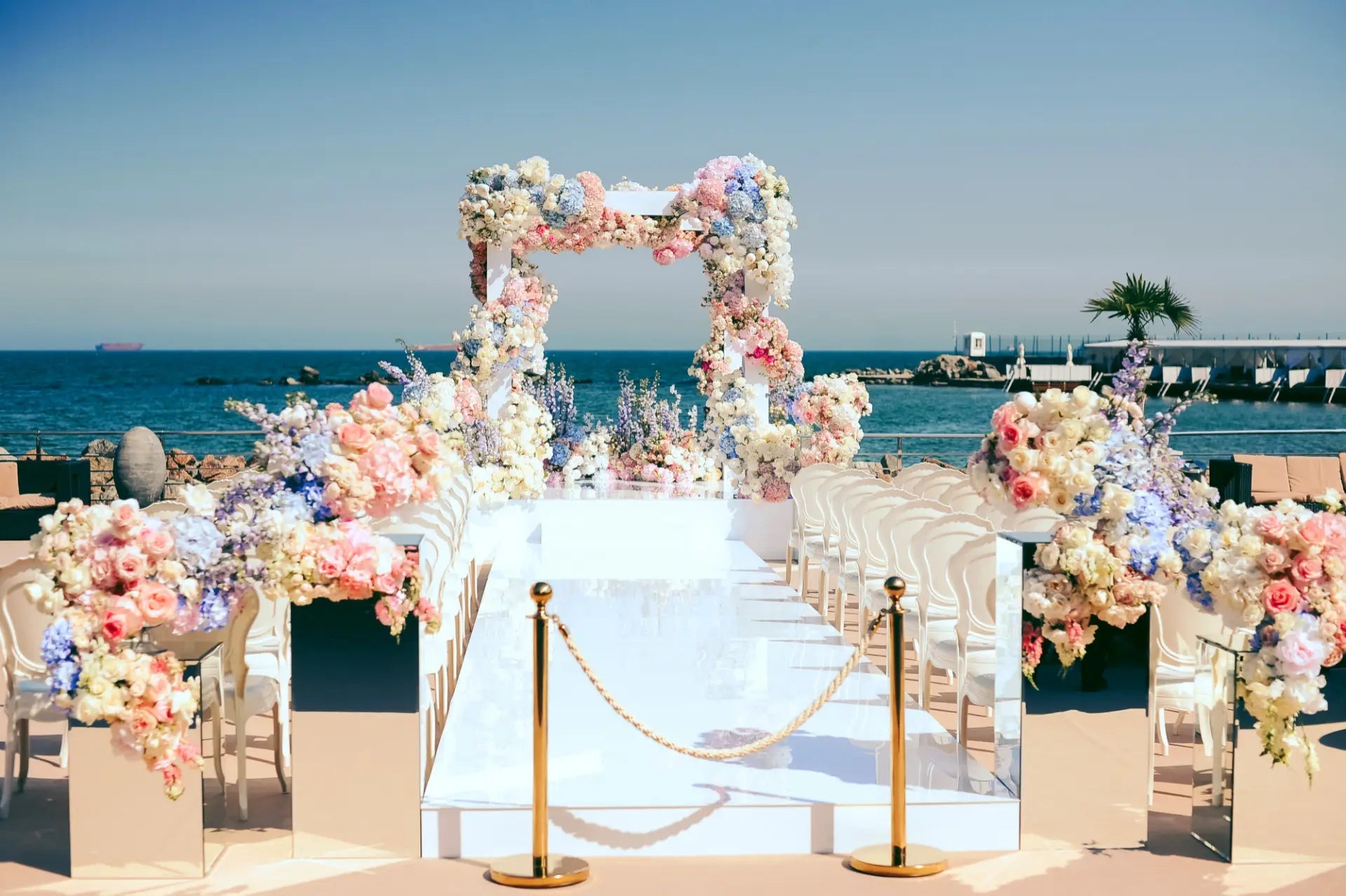 Decorative floral archway setup for a wedding ceremony by the ocean.