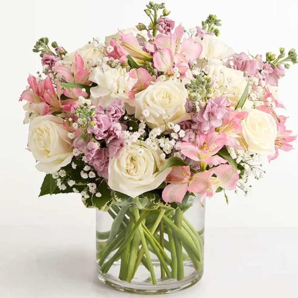 Bouquet of pink and white flowers in a clear vase on a white background