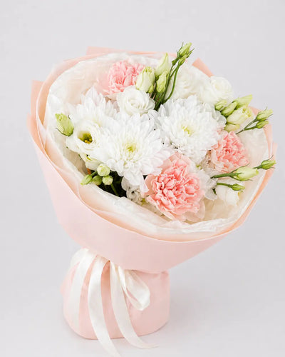 Bouquet of flowers wrapped in white paper with a pink holder on a light gray background