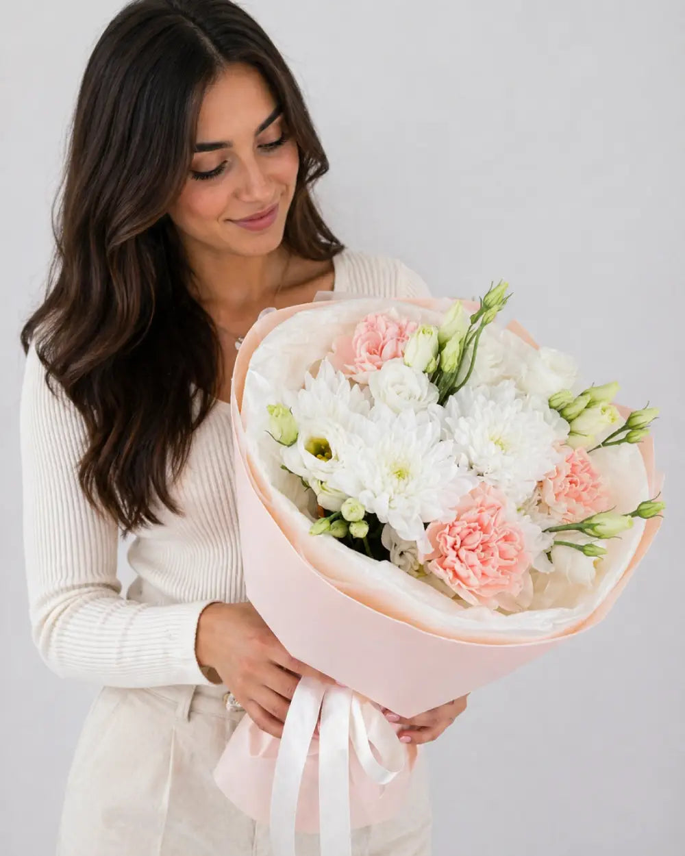 Woman holding a bouquet of flowers against a plain background