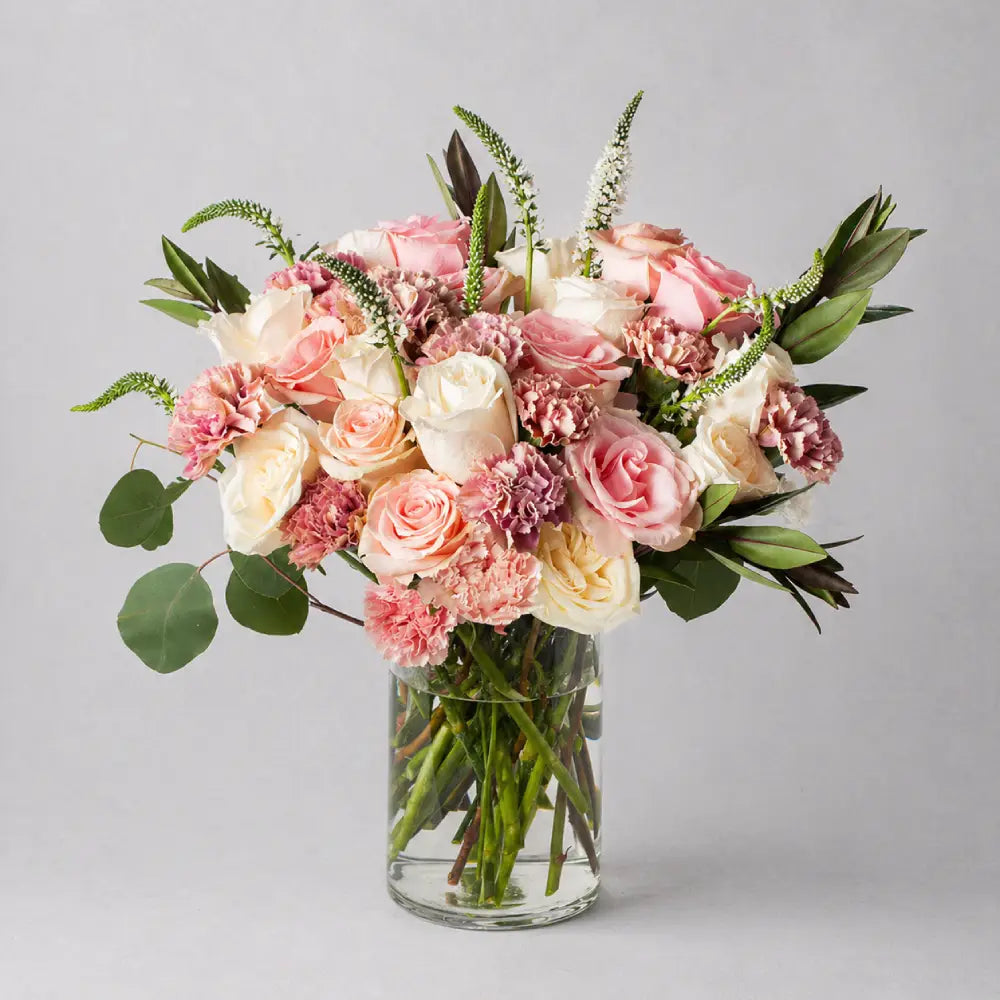 Bouquet of pink and white flowers in a clear vase on a gray background
