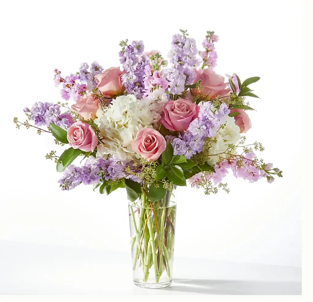 Bouquet of pink, white, and purple flowers in a clear vase on a white background
