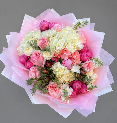 Bouquet of pink and white flowers with pink paper wrapping on a gray background