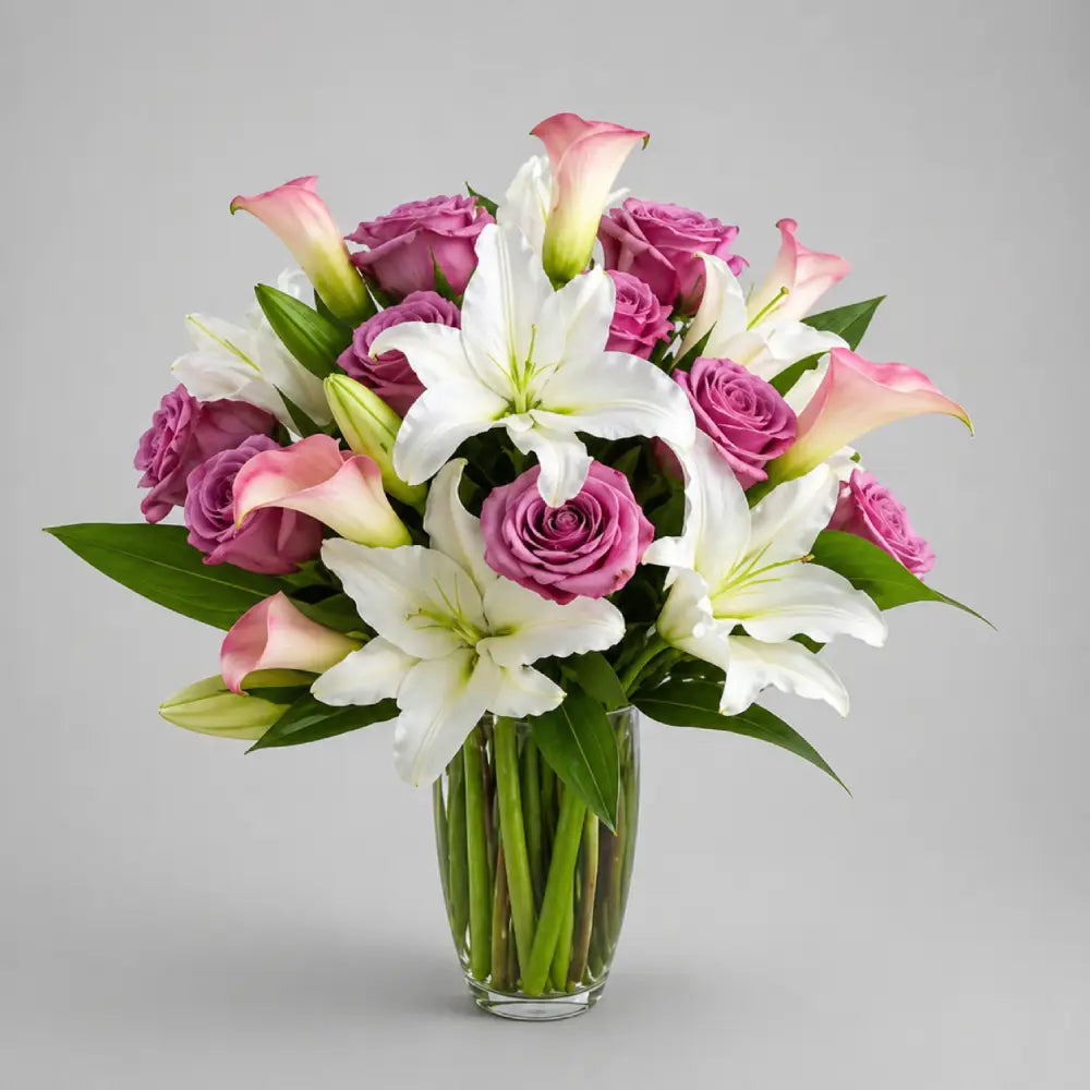 Bouquet of pink and white flowers in a clear vase on a gray background