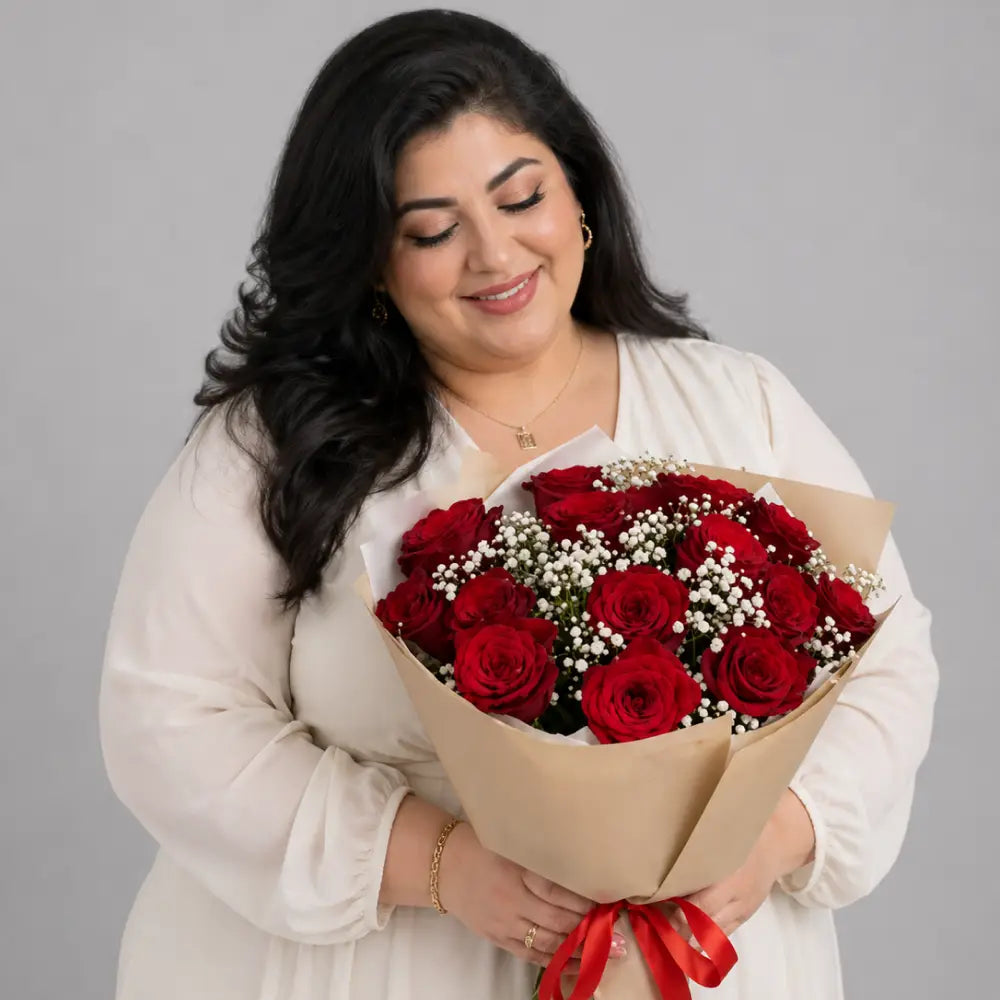 Woman holding a bouquet of red roses against a gray background