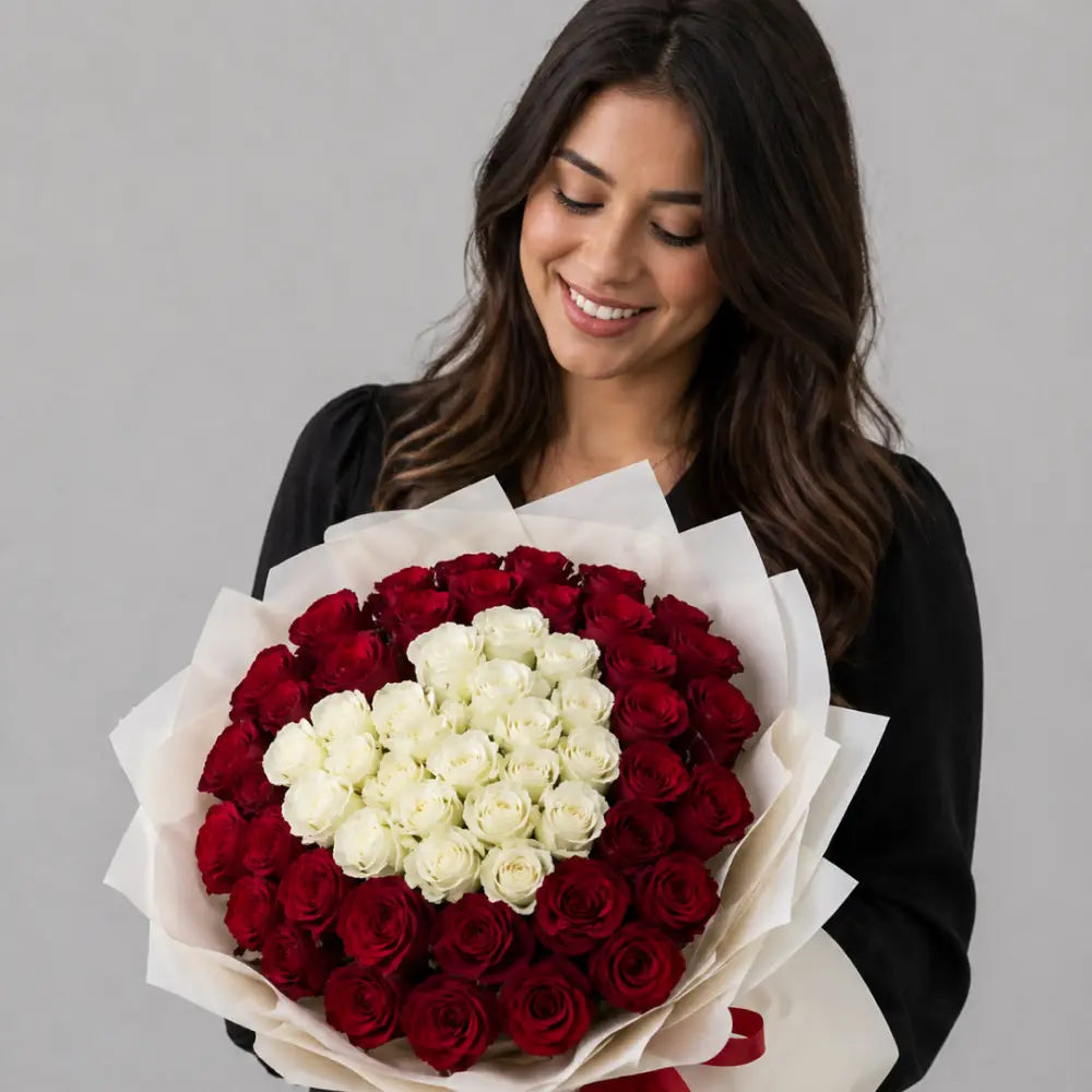 Woman holding a heart-shaped bouquet of red and white roses against a gray background