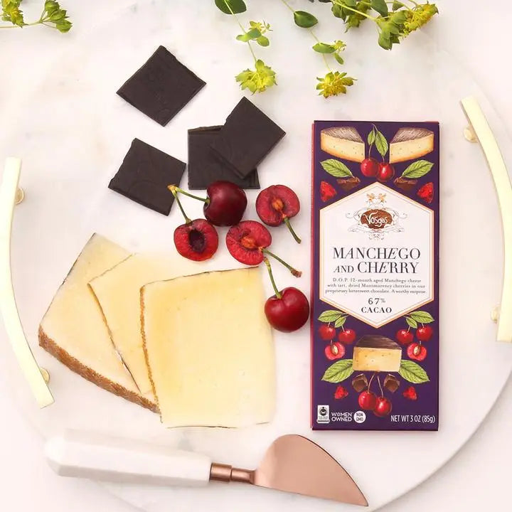 Manchego cheese, dark chocolate, and cherries on a plate with a Vosges Manchego and Cherry chocolate bar.