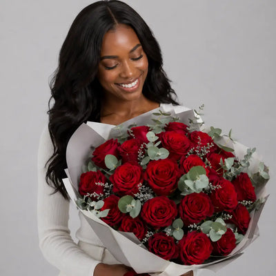 Woman holding a bouquet of red roses against a gray background