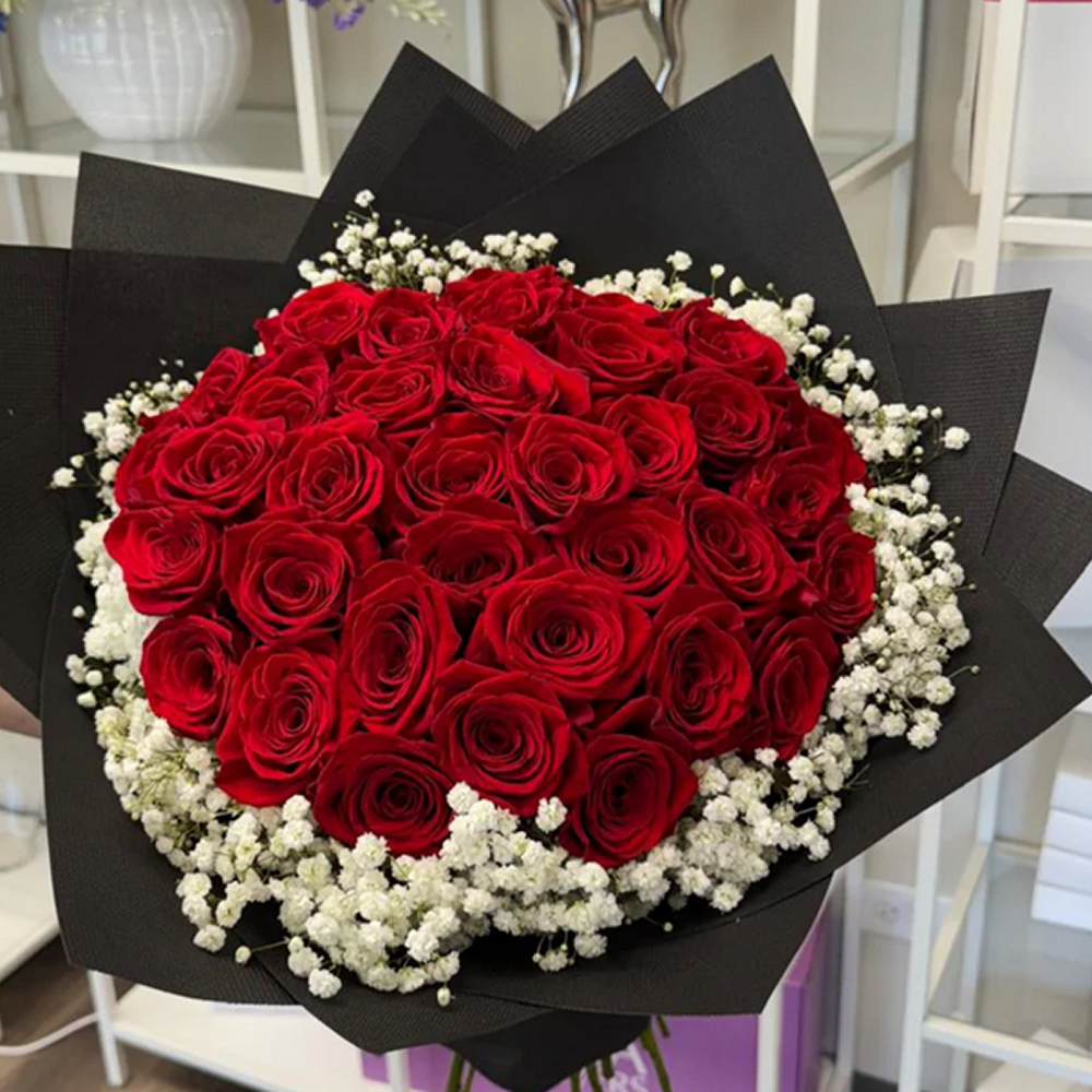 Bouquet of red roses with white accents in black paper packaging