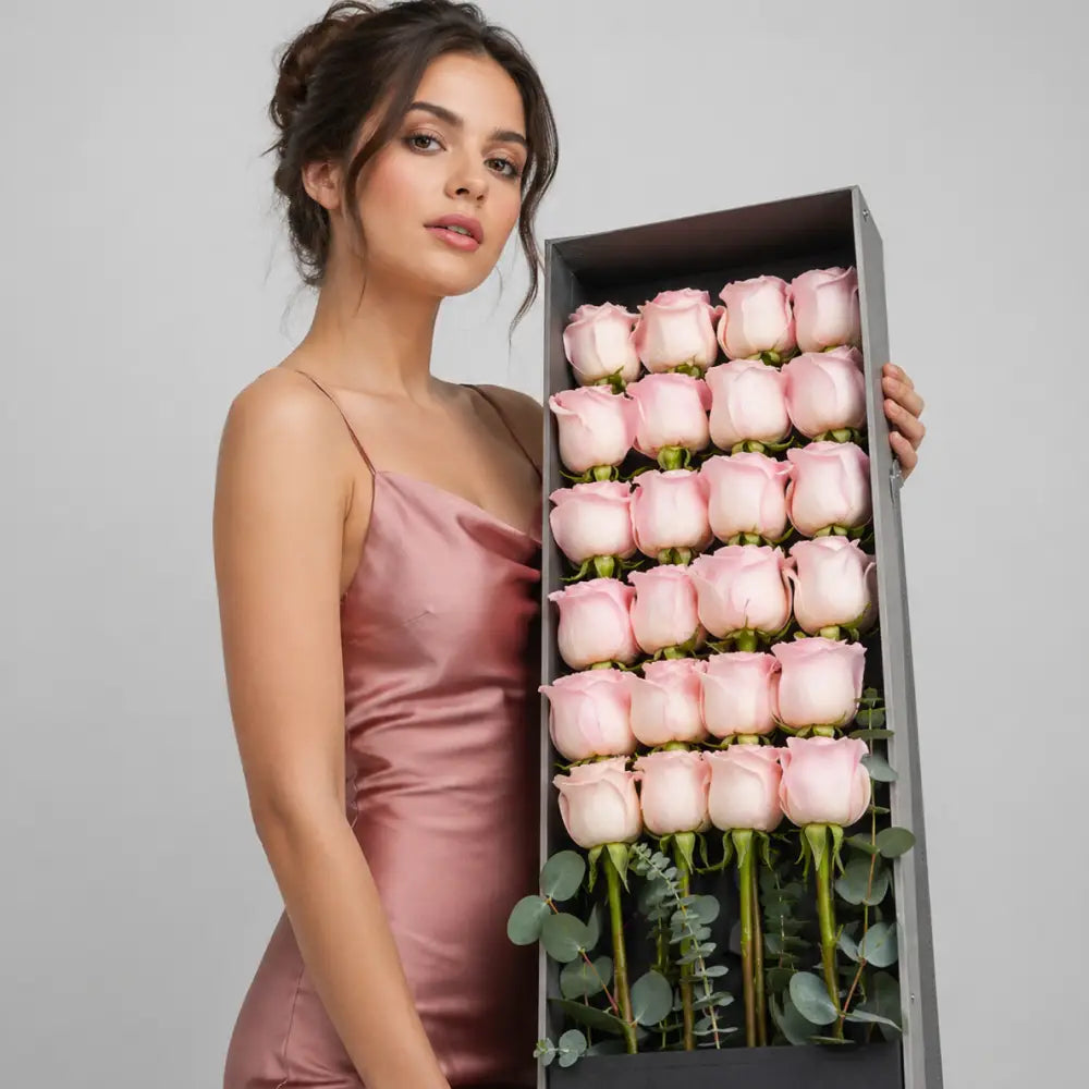 Woman holding a box of pink roses against a gray background