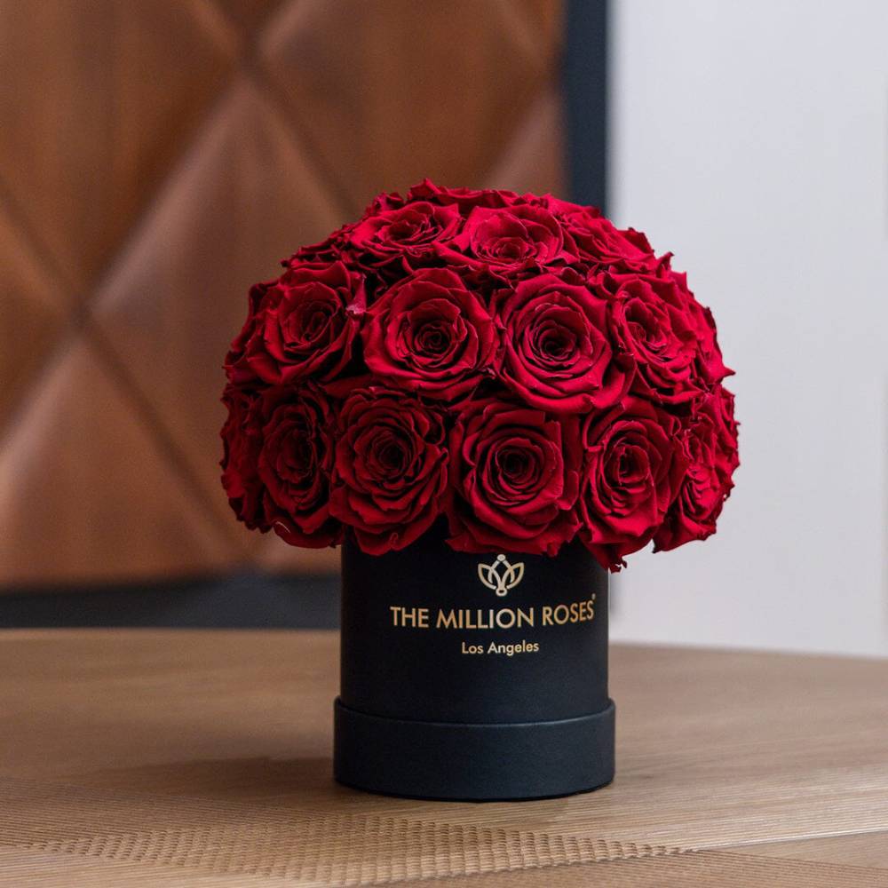 Black box with red roses and 'The Million Roses' branding on a wooden surface.