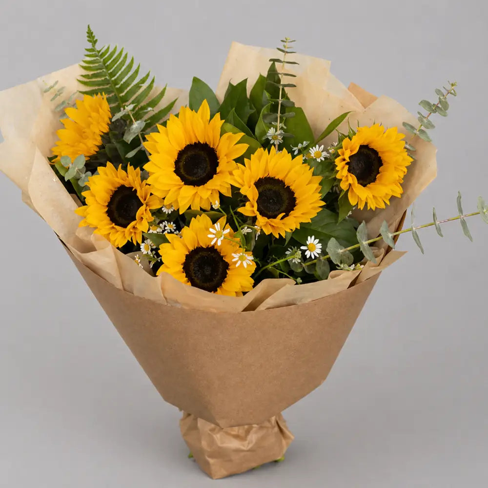 Bouquet of sunflowers wrapped in brown paper on a gray background