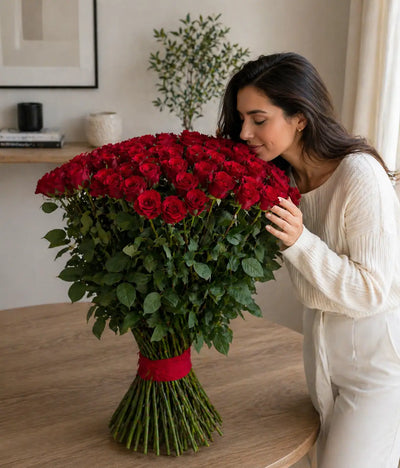 Woman holding a large bouquet of red roses in a home setting