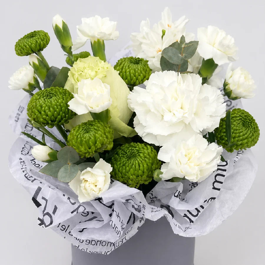 Bouquet of white and green flowers wrapped in newspaper on a light gray background