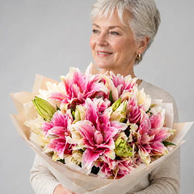 Woman holding a bouquet of pink and white flowers against a gray background