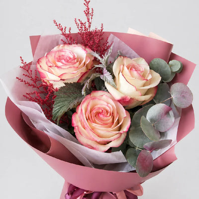Bouquet of pink roses with green leaves and red accents on a light gray background