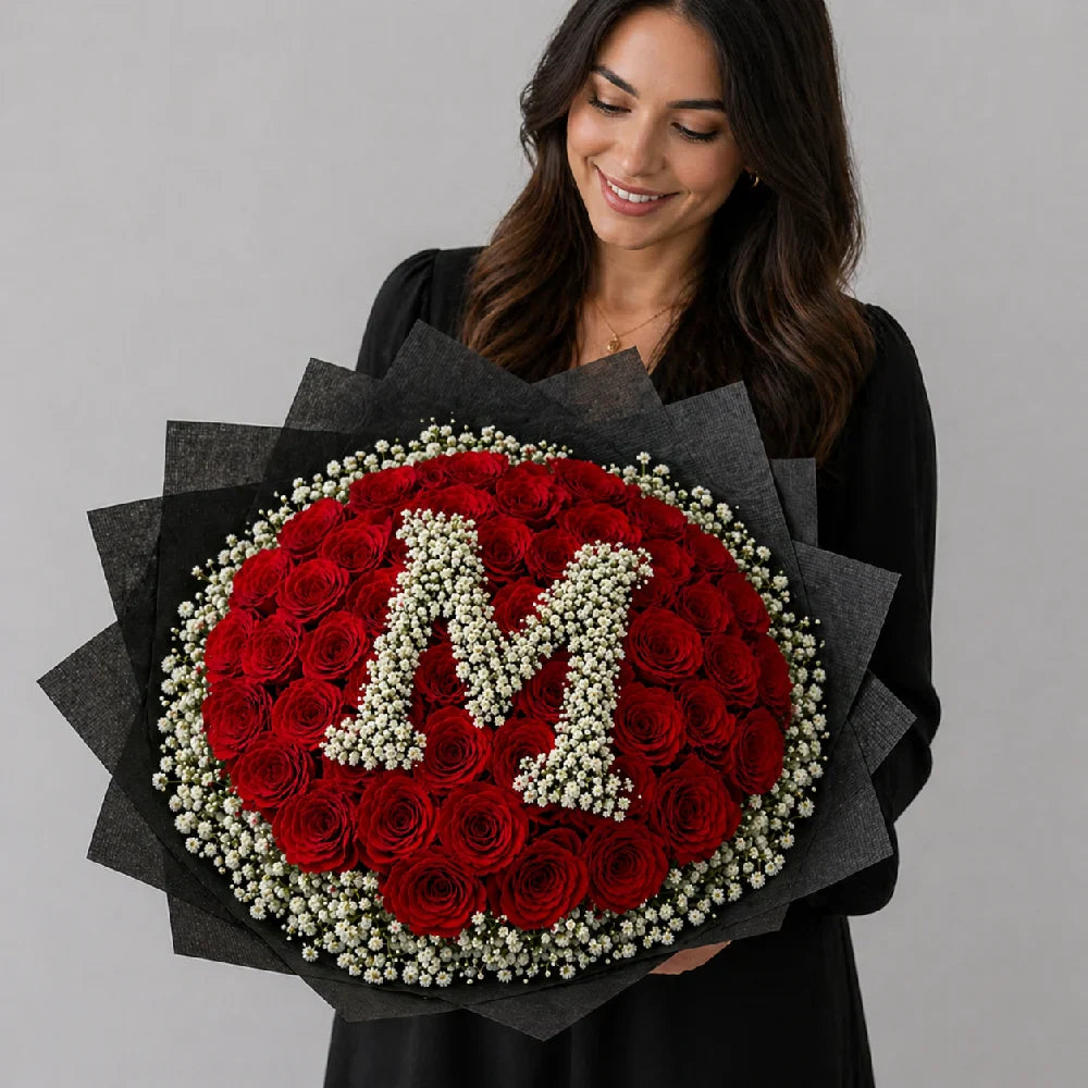 Woman holding a bouquet of red roses and white flowers forming the letter 'M' against a gray background