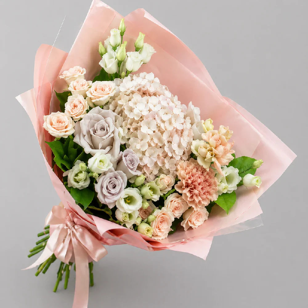 Bouquet of flowers wrapped in pink paper with a gray background