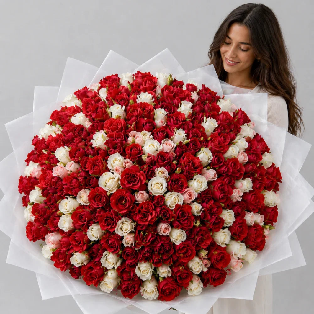 Woman holding a large bouquet of red and white flowers on a gray background