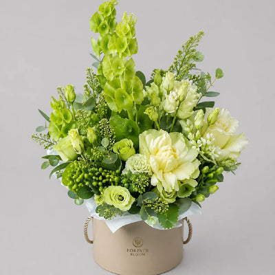 Bouquet of green and yellow flowers in a beige container on a gray background