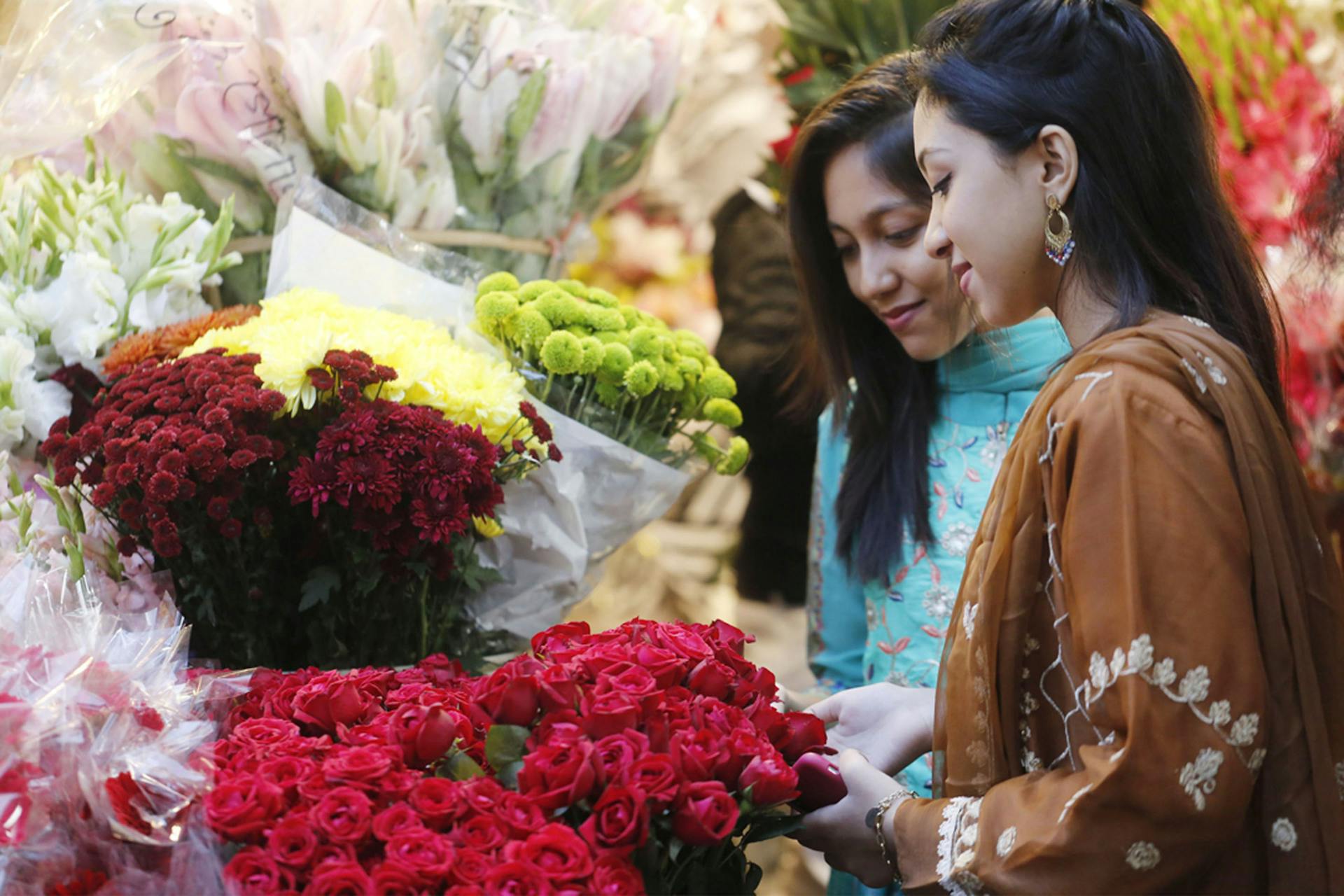 Two women shopping for flowers in a market setting