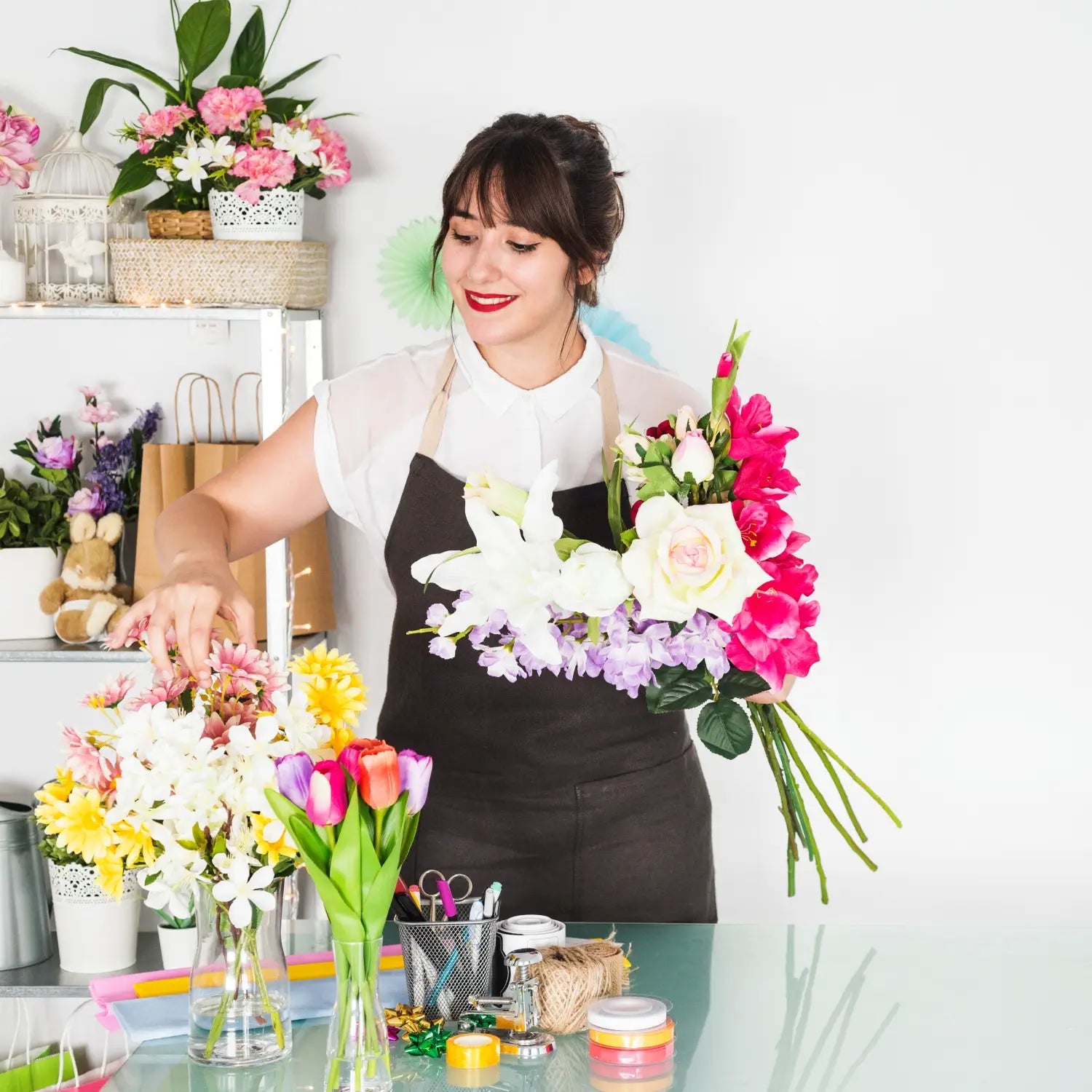 Woman arranging flowers in a floral shop with a white background